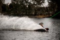 Athletic man in vest balances on wakeboard on the water holding hands on cable