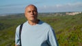 Athletic man walking outdoors with yoga mat. Focused tourist going natural park