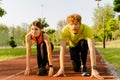 Athletic man and woman getting ready to run on sports track in park Royalty Free Stock Photo