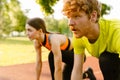 Athletic man and woman getting ready to run on sports track in park Royalty Free Stock Photo