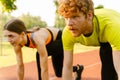 Athletic man and woman getting ready to run on sports track in park Royalty Free Stock Photo