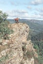 Athletic mature couple stands on a high rock above the white river against the background of the Ural mountains