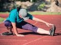 Athletic middle aged woman stretching on red  running track Royalty Free Stock Photo