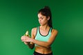 Athletic muscular brunette peels a banana on a green background. Vitamins and healthy nutrition snack during exercise