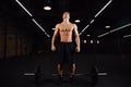 Athletic pumped man bodybuilder stands in front of bar in gym. Fitness male ready to work.