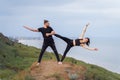 Athletic, pumped up, muscular, beautiful couple in love posing on the edge of the hill. Doing stretching and pair acro yoga on the