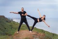 Athletic, pumped up, muscular, beautiful couple in love posing on the edge of the hill. Doing stretching and pair acro yoga on the