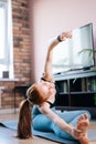 Athletic redhead young woman working out, doing stretching exercise on yoga mat via laptop online Royalty Free Stock Photo
