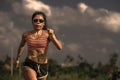 Athletic runner Asian woman training running series workout working hard outdoors on field background in harsh contrast light spor Royalty Free Stock Photo