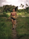 Athletic runner Asian woman training running series workout working hard outdoors on field background in harsh contrast light spor Royalty Free Stock Photo