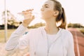 Athletic runner drinks water from a plastic bottle after running. A girl quenches her thirst after outdoor fitness classes