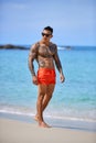 Athletic tattooed guy walking at the the tropical beach Royalty Free Stock Photo