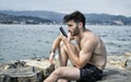 Young man by the sea sending voice message on phone Royalty Free Stock Photo