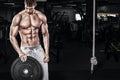 Athletic shirtless young sports man - fitness model holds the dumbbell in gym. Copy space fore your text. Royalty Free Stock Photo