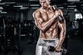 Athletic shirtless young sports man - fitness model holds the dumbbell in gym. Copy space fore your text. Royalty Free Stock Photo