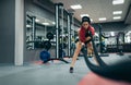 Athletic sportive young fit female working out in functional training gym doing crossfit exercise with battle ropes, copyspace for Royalty Free Stock Photo