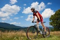 Athletic sportsman cyclist in sportswear and helmet riding a bicycle in high grass Royalty Free Stock Photo