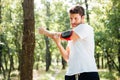 Athletic sportsman with handband standing and doing exercises in forest