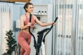 Athletic and sporty woman running on elliptical running machine at gaiety home.