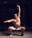 Athletic strong man doing the exercises with kettlebell on dark