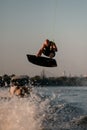 Athletic strong muscular man skillfully jumping on splashing wave on wakeboard