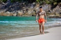 Athletic tattooed guy walking at the the tropical beach Royalty Free Stock Photo