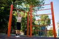 Athletic teenager getting ready to perform the exercise. Street workout on a horizontal bar in the school park