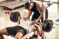 athletic trainer helping sportsman lifting barbell with heavy weight plates