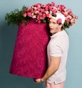 Man delivery guy with rose at ear and lipstick kiss on cheek is holding carrying huge valentines day box with flowers Royalty Free Stock Photo