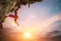 Athletic Woman climbing on overhanging cliff rock with colorful sunset sky background Royalty Free Stock Photo