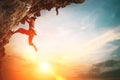 Athletic Woman climbing on overhanging cliff rock with sunset sky background