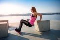 Athletic  woman doing squatting exercise in sunny park near the lake. Concept of wellness and healthy lifestyle Royalty Free Stock Photo