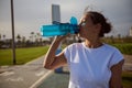 Athletic woman drinking water from sports bottle after hard workout outdoors