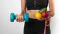 Athletic woman with fruits and vegetables, dumbbells and measuring tape - diet, training, trainer nutritionist