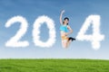 Athletic woman jumping with shaped clouds of 2014 Royalty Free Stock Photo