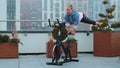 Athletic woman makes twine training routine on spinning stationary bike on house roof, weight loss Royalty Free Stock Photo