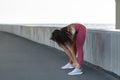 Athletic woman in pink legging standing on embankment, stretching muscles making functional training, doing exercises for legs