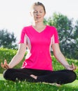 Athletic woman in pink T-shirt is sitting and meditating