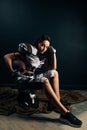 Athletic woman sits on helmet in American football uniform and holds ball Royalty Free Stock Photo