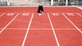 Athletic woman in sport clothes on starting line prepares to run at the running on athletic track. Female runner ready for sports Royalty Free Stock Photo