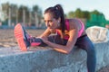 Athletic woman stretching her hamstring, legs exercise training fitness before workout outside on a beach at summer Royalty Free Stock Photo