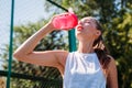 Athletic young blond woman drinks water from sports cup with cool illuminating water Royalty Free Stock Photo