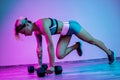 Athletic young blonde woman doing heavy dumbbell exercise in the gym in neon lights. Royalty Free Stock Photo