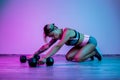 Athletic young blonde woman rest after heavy dumbbell exercise in the gym in neon lights. Royalty Free Stock Photo