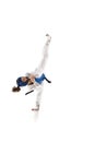 Athletic young girl in dobok and blue helmet practicing, training taekwondo isolated over white background