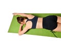 Athletic young girl lies face down on a yoga mat and stretches her arms forward in front of her. Royalty Free Stock Photo