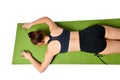Athletic young girl lies face down on a yoga mat and stretches her arms forward in front of her. Royalty Free Stock Photo