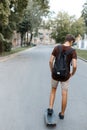 Athletic young handsome hipster man in trendy summer clothes with a black backpack rides snowboarding. Fashionable guy Royalty Free Stock Photo