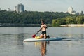 Athletic young man actively spends time on the water, swims on a sup board, paddles and looks away. Surfing on the lake on a sup