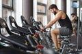 Athletic young man with a beard is engaged on a stationary bike in the gym